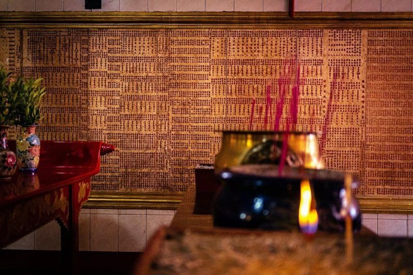 Un autel chinois traditionnel, avec des bâtonnets d’encens, une table rouge et une plante en pot. 2