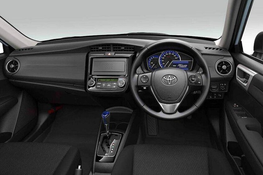 A car's interior with a steering wheel, dashboard, gear shift, and center console. 3