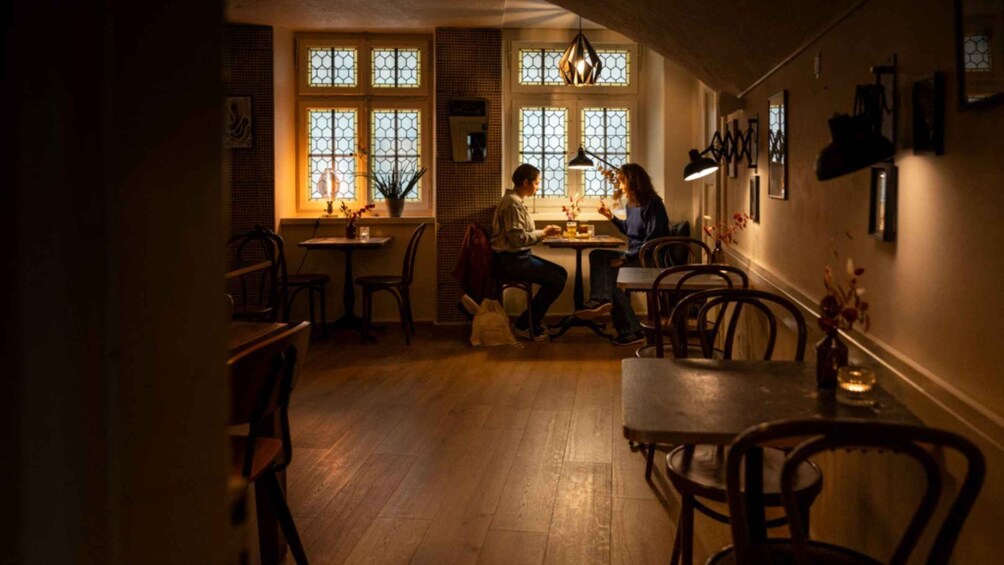 A dimly lit café with wooden furniture and large windows with geometric patterns. 5