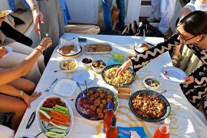 A group of people at a picnic with various dishes and drinks on a table. 5