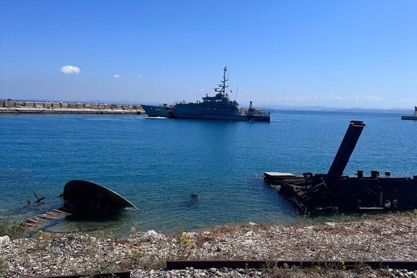 Un gran buque de guerra atracado en un muelle, con una pequeña embarcación en primer plano. 3