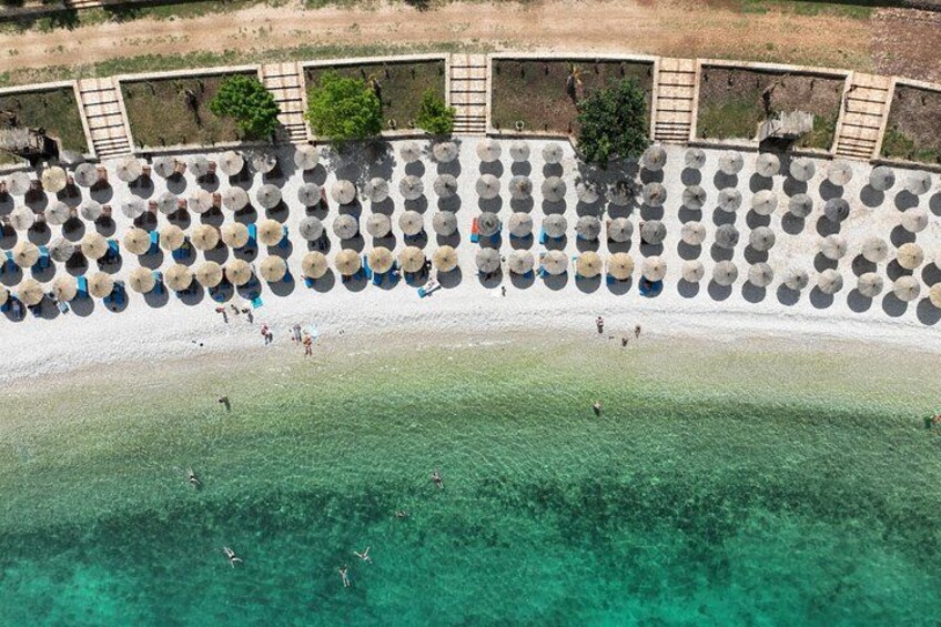 Una playa con agua turquesa cristalina, una orilla de arena y una hilera de sombrillas. 2