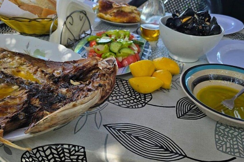 Et bord med stegt fisk, en salat, en skål oliven og et brød. 4