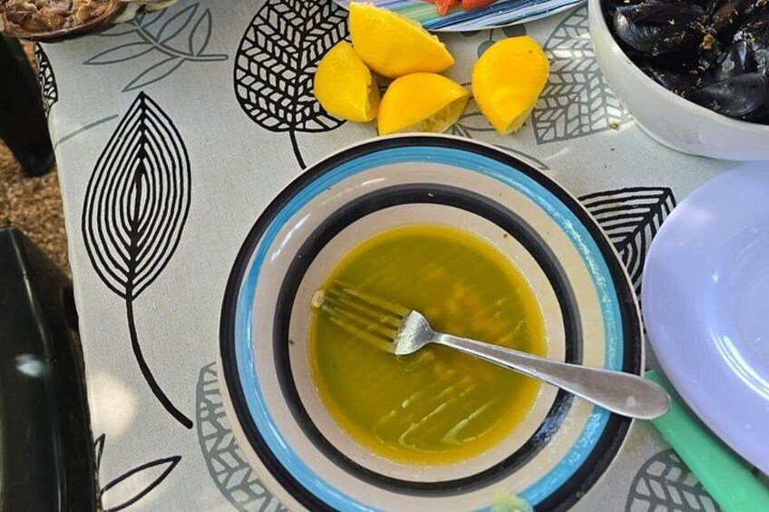En skål suppe med en ske på en mønstret dug, citroner og en skål med sorte ting. 3