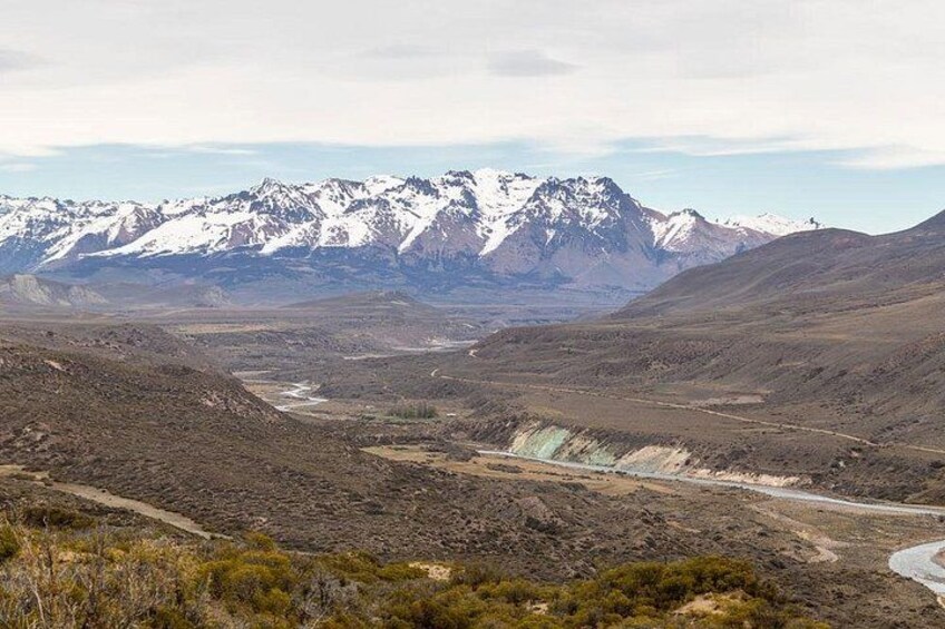 A mountainous landscape with snow-capped peaks, a winding river, and sparse vegetation. 3
