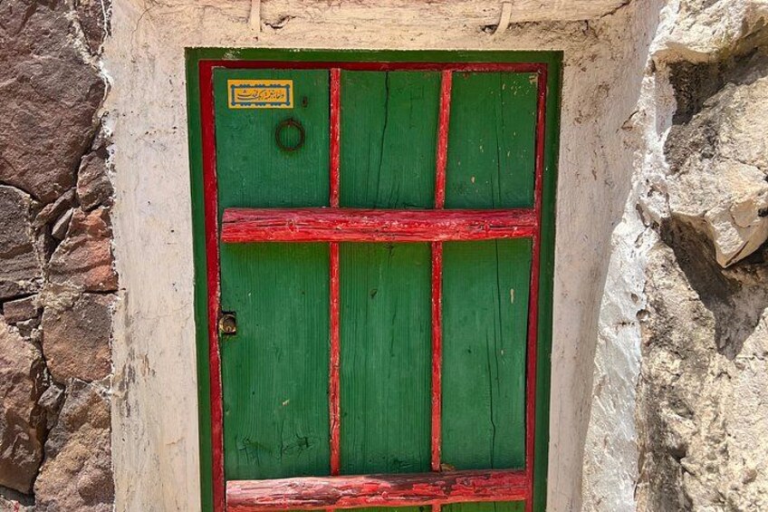 A green door with red accents and a yellow sign. 2