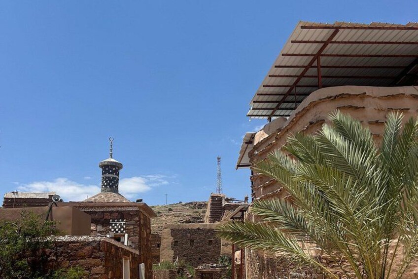 A mosque with a minaret, palm trees, and a clear blue sky. 5