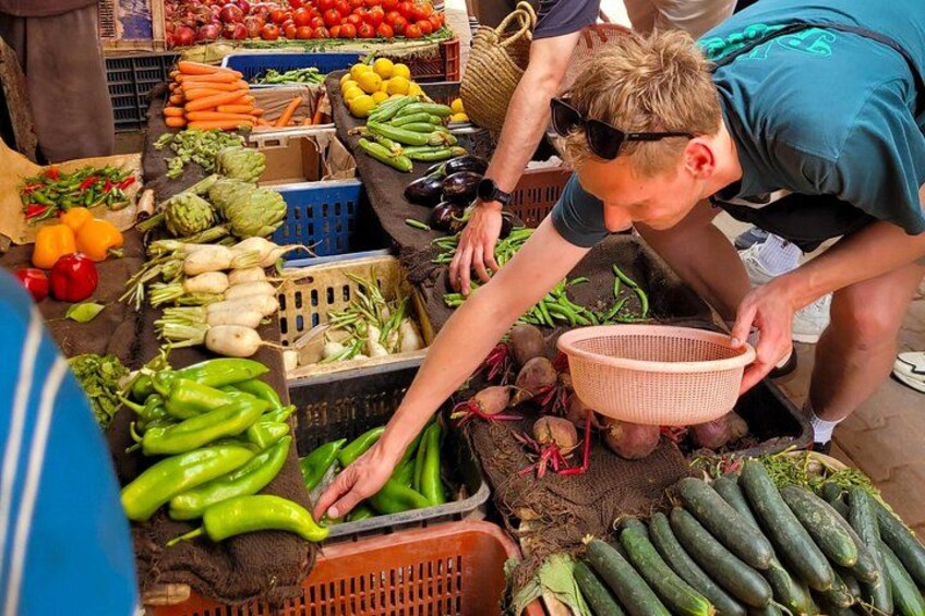 Eine Person wählt Gemüse an einem Marktstand aus. 1