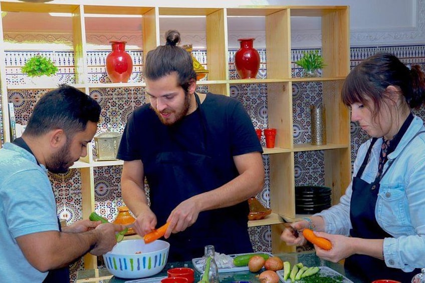 Drei Personen bereiten Essen mit Gemüse und einer Schüssel zu. 2