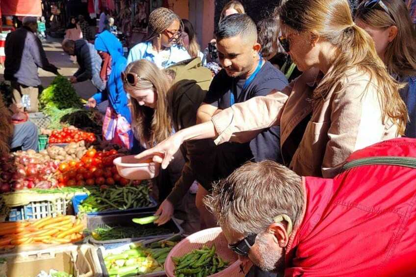 Menschen kaufen auf einem Markt ein, auf dem verschiedene Gemüsesorten ausgestellt sind. 3