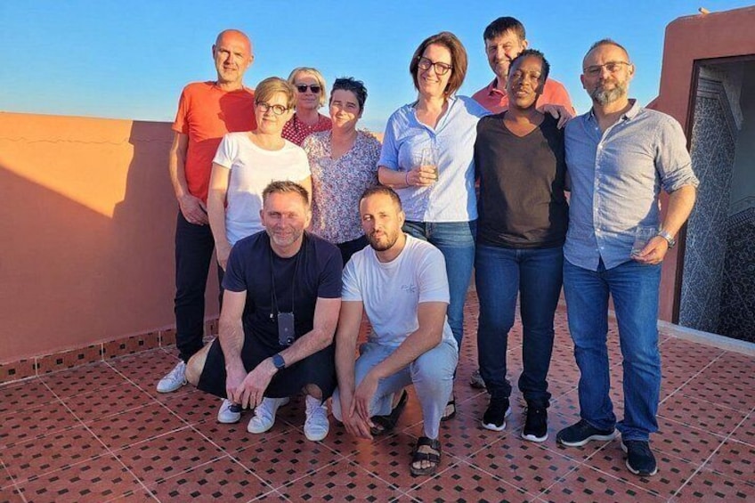 Eine Gruppe von Menschen auf einer Dachterrasse mit einem gemusterten Boden und blauem Himmel im Hintergrund. 4