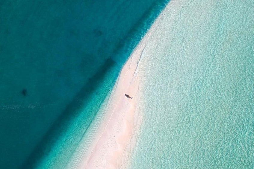 Vista aérea de una playa con aguas turquesas cristalinas y una franja arenosa estrecha. 3