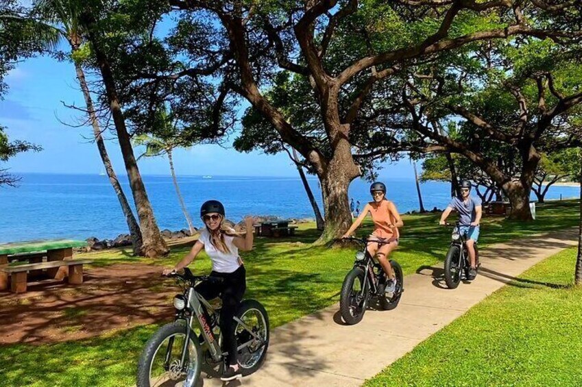 Three people riding bicycles on a path near a body of water. 5