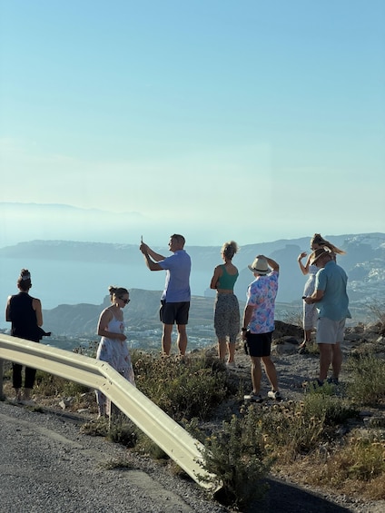 A group of people standing on a rocky hillside overlooking a coastal landscape. 3
