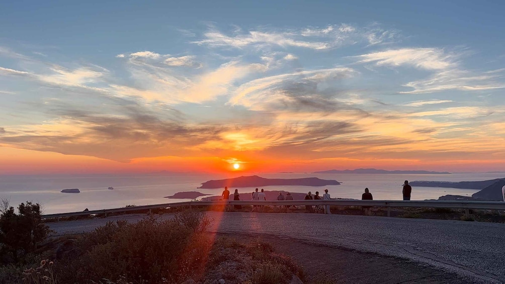 A sunset over a coastal landscape with a bridge and people observing the view. 2