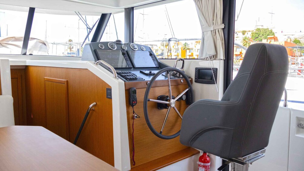 A boat's control station with a steering wheel, navigation screens, and a communication device. 5