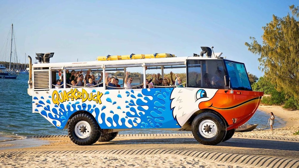 A colorful tour bus with a water-themed design, parked by the seaside. 2