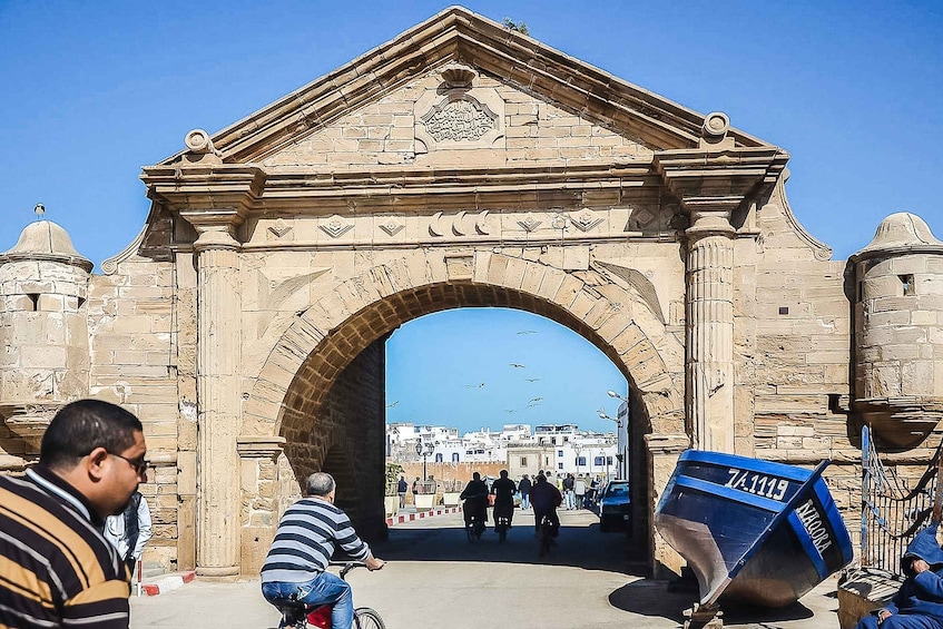 An ancient stone archway with inscriptions, leading to a town. 3