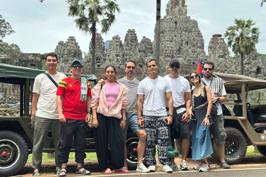 Un grupo de personas posando frente a una estructura de piedra histórica con palmeras al fondo. 5