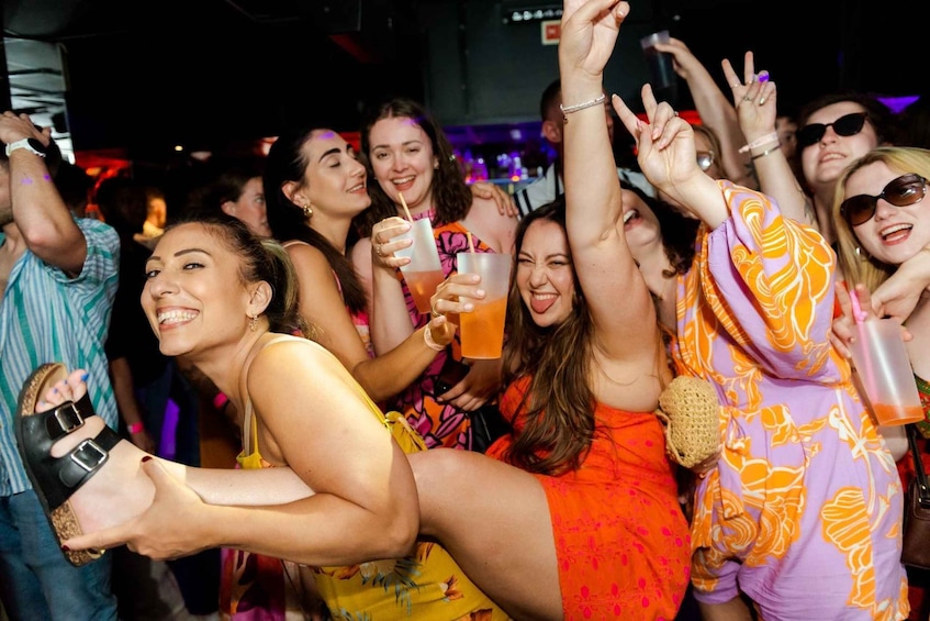 A group of people at a social event, some holding drinks and others making hand gestures. 1