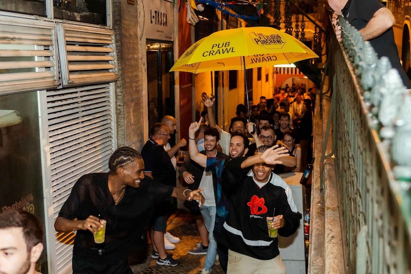 A group of people exiting a building, some holding drinks and an umbrella. 2