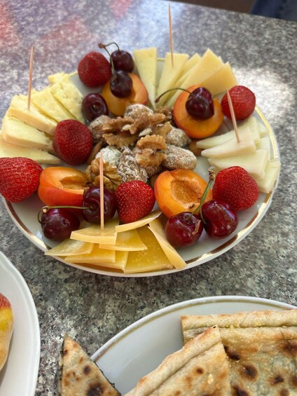 A fruit and cheese platter with various fruits, nuts, and cheese slices on a plate. 1