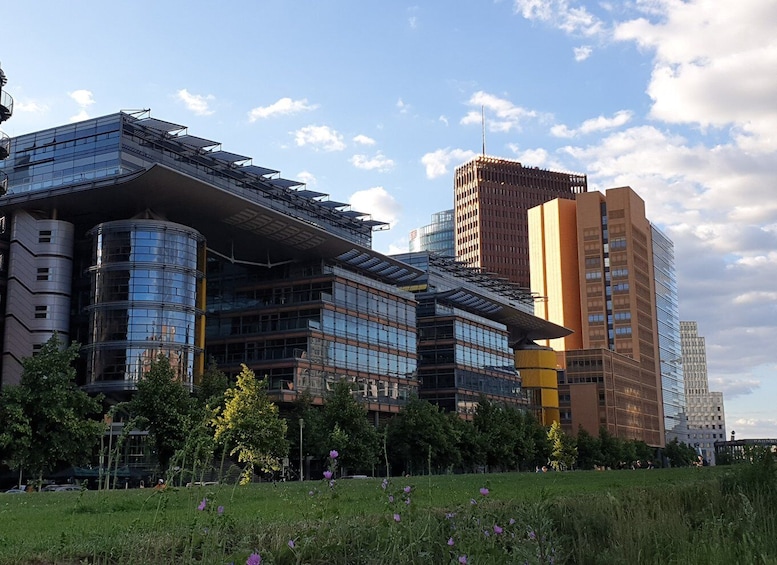 A modern urban landscape with contemporary architecture, including a building with a curved glass facade and another with a grid-like pattern. 5