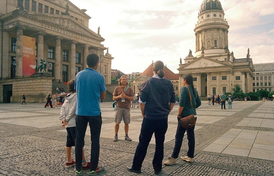A group of people standing in a plaza with historical buildings in the background. 3