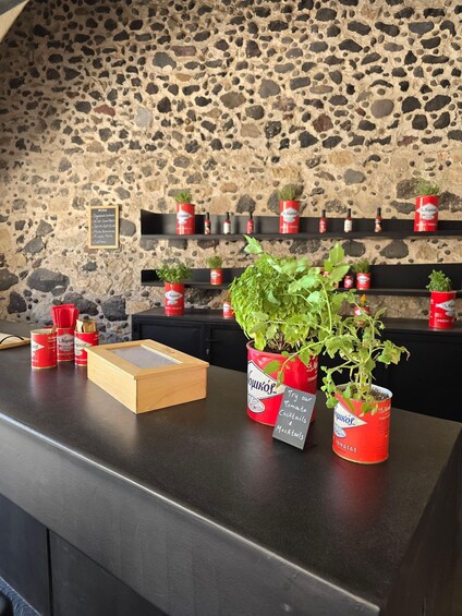 A bar counter with potted plants in tomato cans, a menu board, and a wooden box. 5