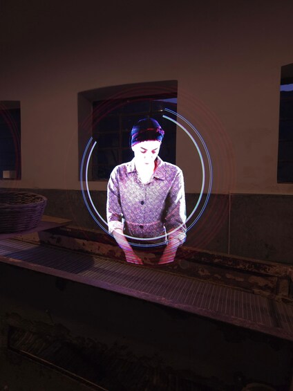 A person standing in front of a wall with a circular light pattern. 4