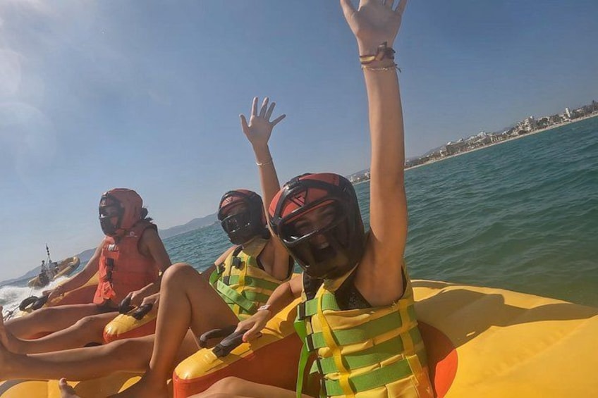 People on a yellow raft in the water with a beach and buildings in the background. 3