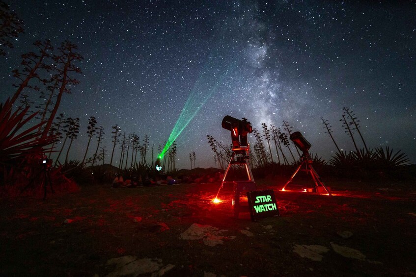 Cielo nocturno estrellado con telescopios y un cartel que dice 'STAR WATCH'. 1