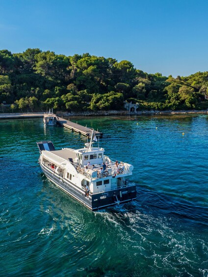 A boat docked at a pier with a forested hillside in the background. 5