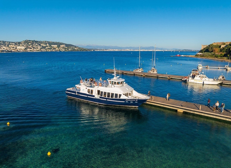 A boat docked at a pier with clear blue water and a distant cityscape. 2
