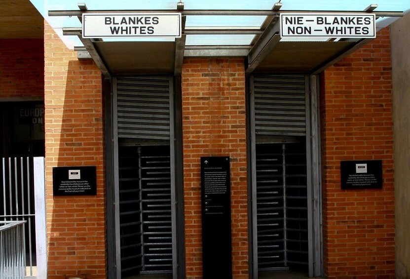 A building entrance with signs reading "BLANKES WHITES" and "NIE - BLANKES NON - WHITES". 5