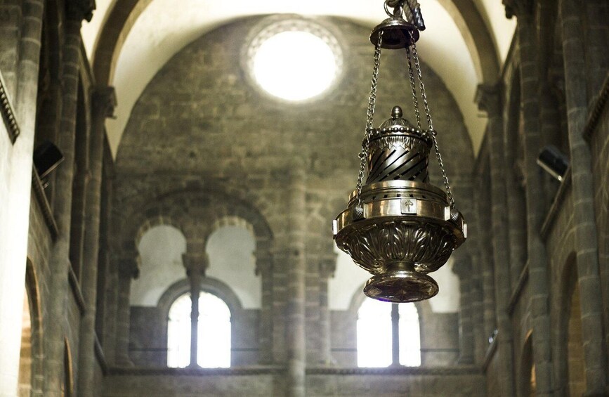 Ein hängender Metallkronleuchter in einer Kathedrale mit Rundbogenfenstern und einer Kuppel. 2