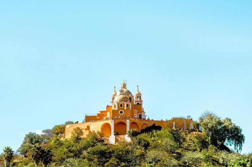 A church with a dome and bell tower, surrounded by trees on a hill. 2