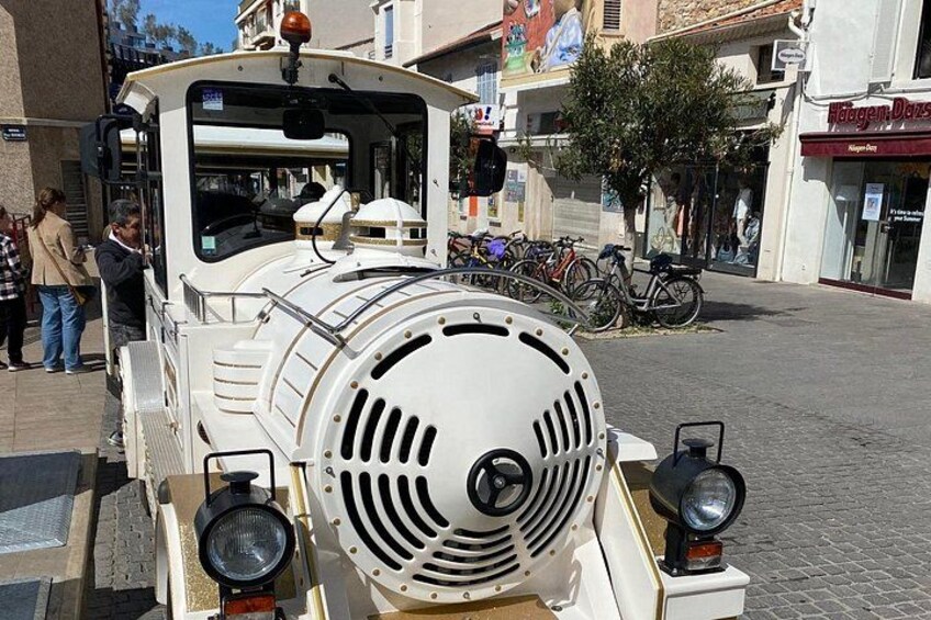 Une locomotive ancienne est garée sur une rue pavée, avec des vélos et des piétons en arrière-plan. 5