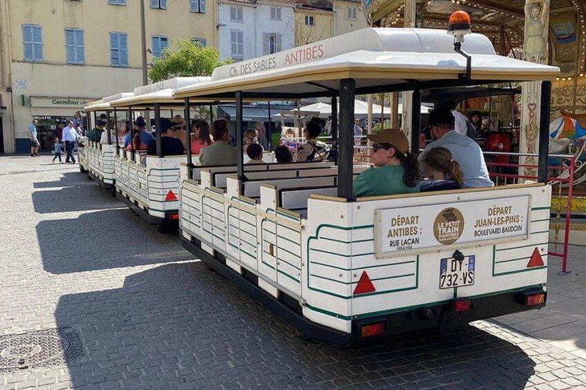 Un tram touristique rempli de passagers est garé dans une rue pavée. 4