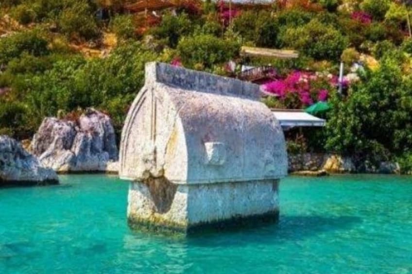 Una estructura de piedra en aguas turquesas cristalinas, rodeada de exuberante vegetación y flores de colores. 1
