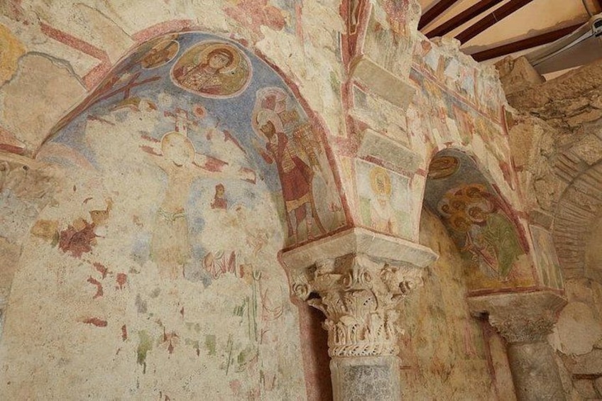 Interior de un edificio histórico con frescos y columnas de piedra. 3