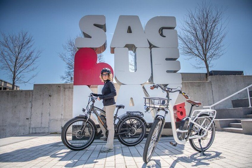 A person standing next to a sign with the word 'SAGE' and two bicycles. 5
