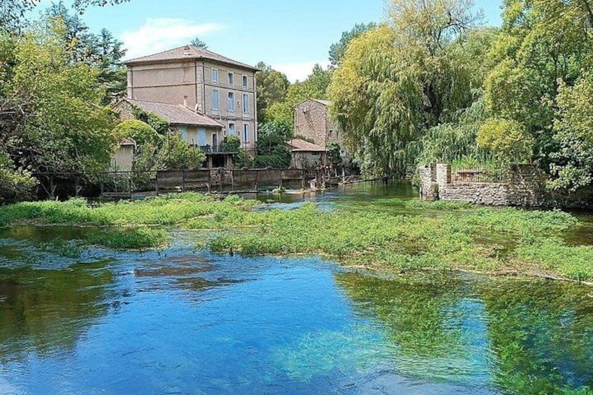 Ein Fluss mit klarem Wasser, umgeben von Grünflächen und Gebäuden. 5