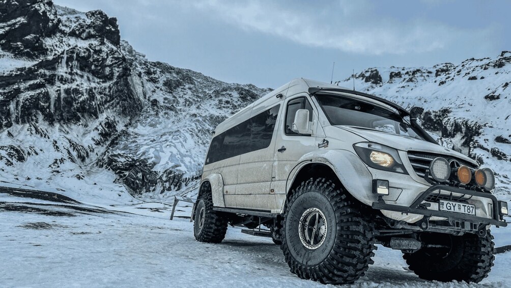Un VUS blanc équipé de pneus tout-terrain et d’un porte-bagages sur le toit, garé sur une montagne enneigée. 2