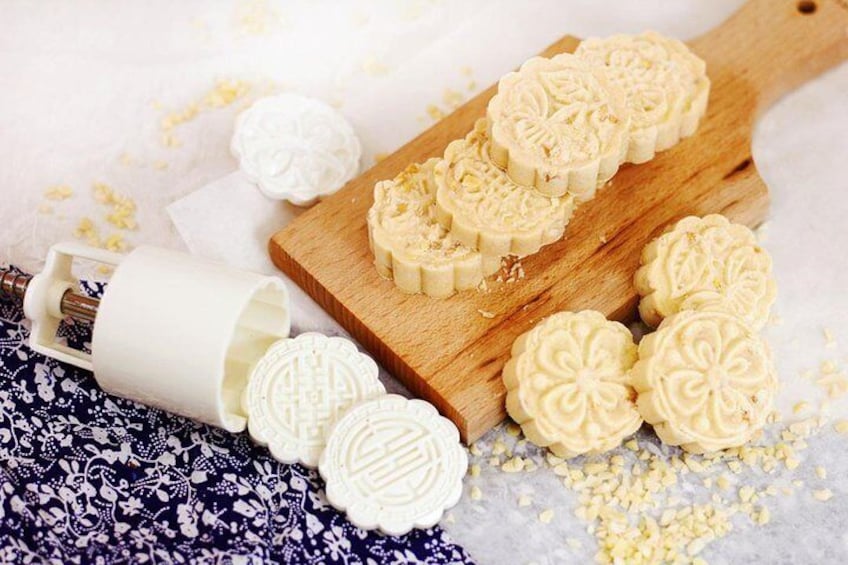 Mooncakes on a wooden board and a rolling pin on a patterned cloth. 1