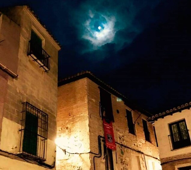 A moonlit night sky above a building with a red banner. 2