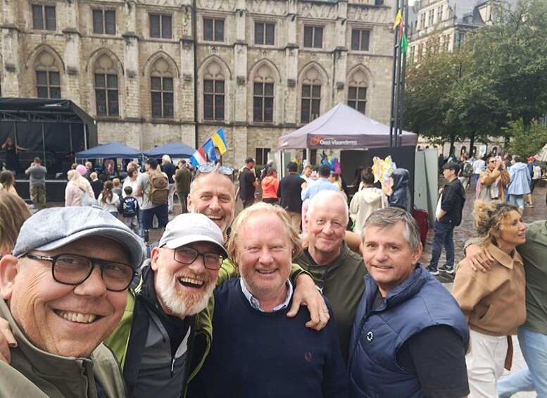 Eine Gruppe von Menschen vor einem historischen Gebäude mit Rundbogenfenstern und einer Fahnenstange. 4