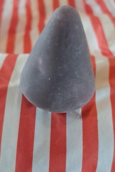 Ein grauer Stein auf einem Hintergrund aus gestreiftem Stoff. 2