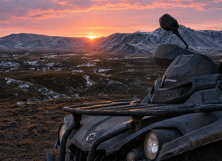 A quad bike in a snowy landscape with mountains in the background and a sunset. 2
