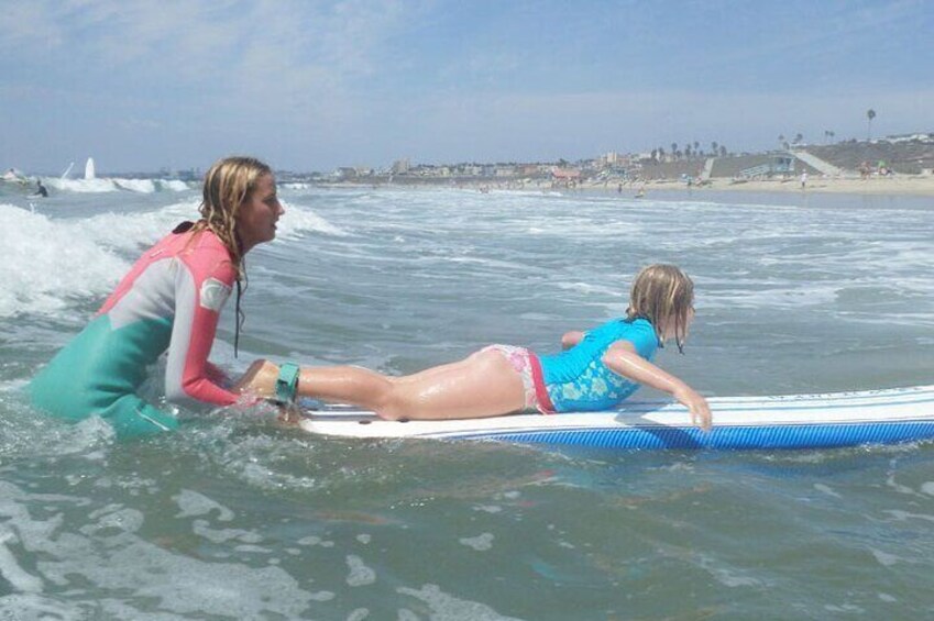 Instructor helps a girl catch a wave. 